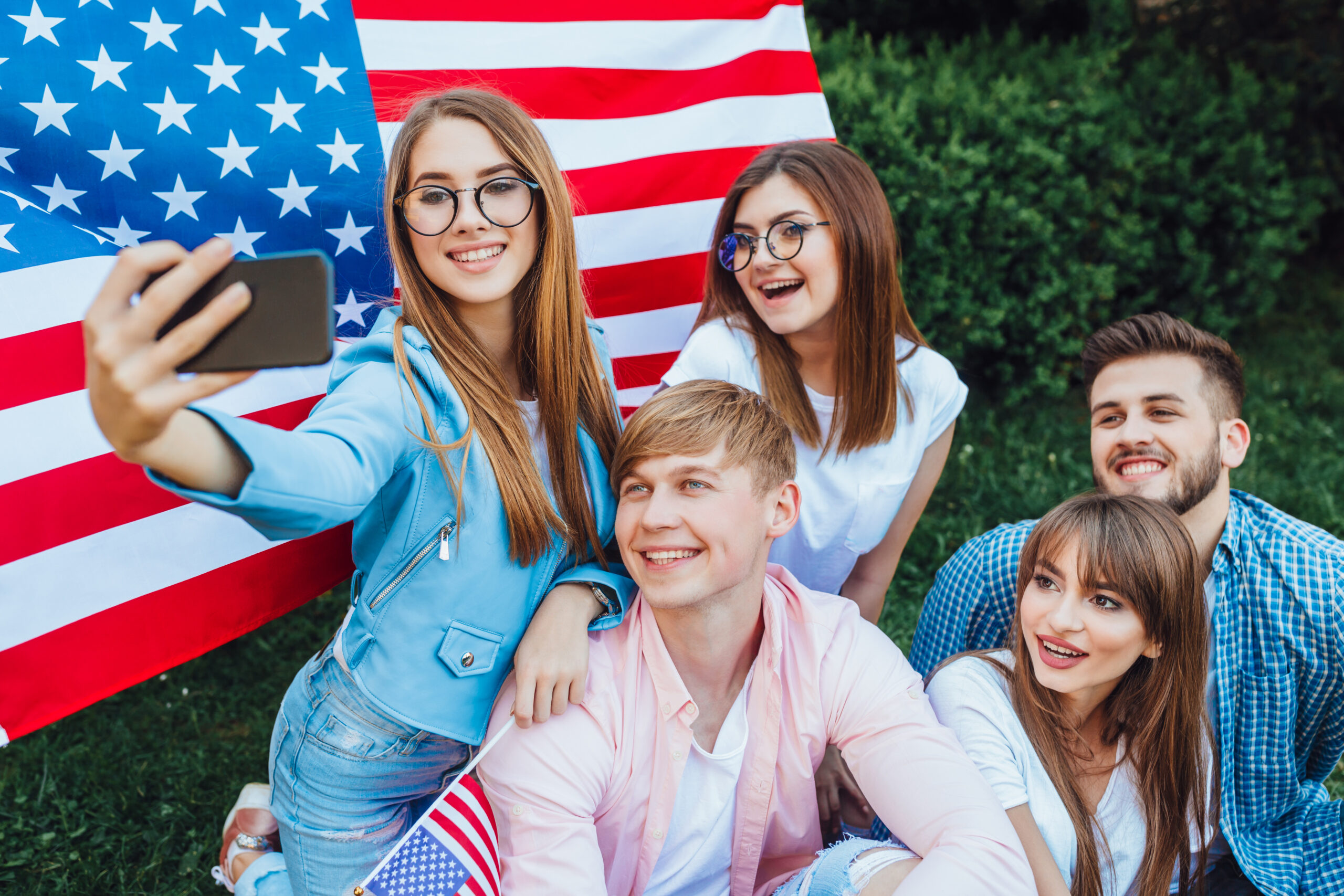 This is the US Independence Day! A group of young Americans doing sephi against the background of the American flag. Mobile phone close up.