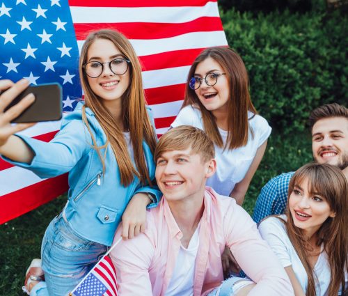 This is the US Independence Day! A group of young Americans doing sephi against the background of the American flag. Mobile phone close up.